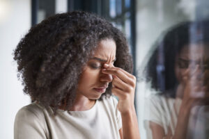 woman with headache holding her sinuses